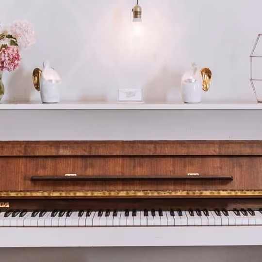 Białe pianino z odsłoniętą klawiaturą w sali restauracji